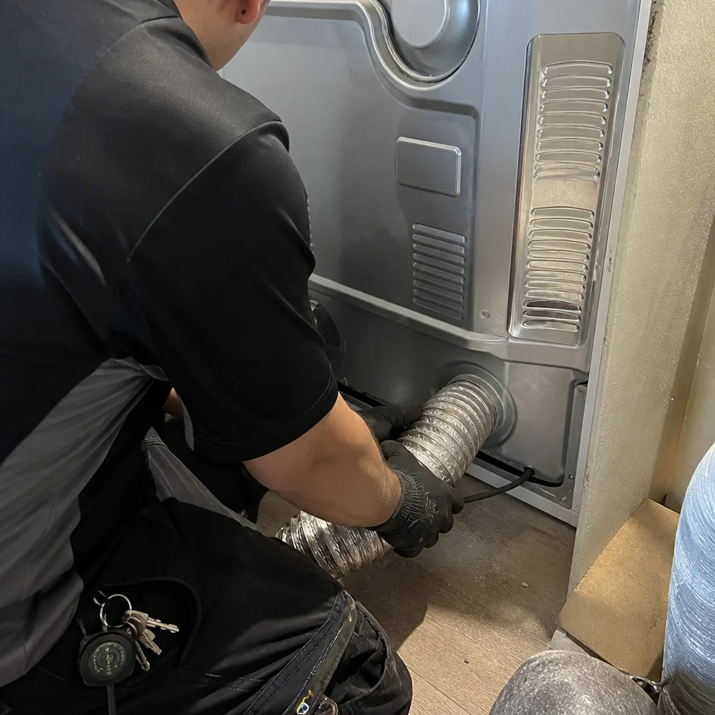 Technician connecting foil dryer vent hose during professional dryer duct maintenance